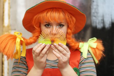 Young girl in the costume of Pippi Longstocking playing with the rainbow spiral spring toy clipart