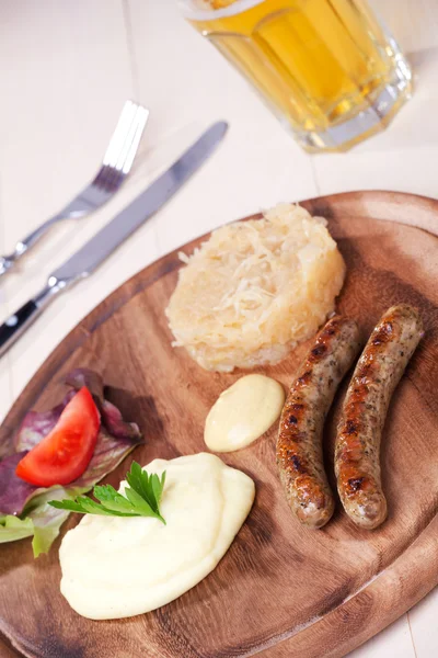 Two bratwurst sausages on a wooden plate — Stock Photo, Image