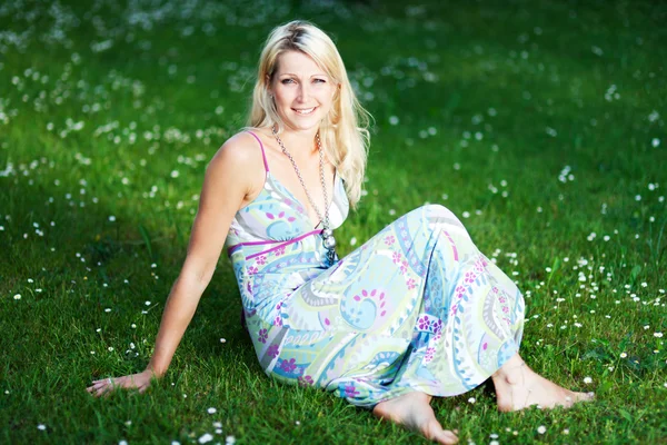 Genç kadın bir yaz aylarında çim üzerinde elbise — Stok fotoğraf