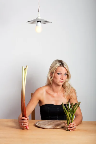 Young woman sitting with rhubarb and asparagus — Stock Photo, Image