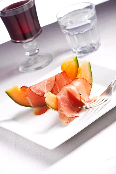 Plátky šunky a meloun na desce — Stock fotografie