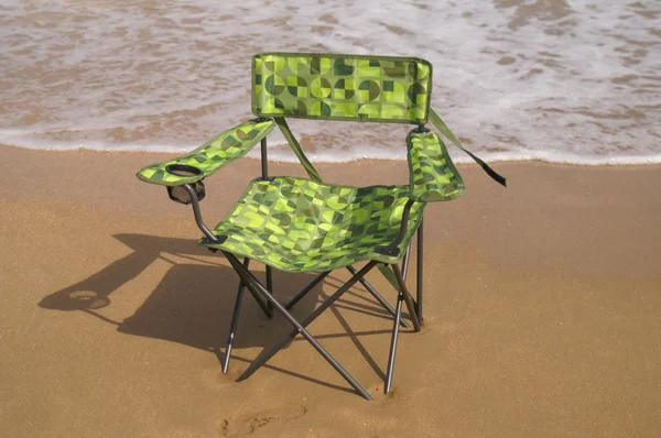 Grüner Stuhl im Sand am Meer. — Stockfoto