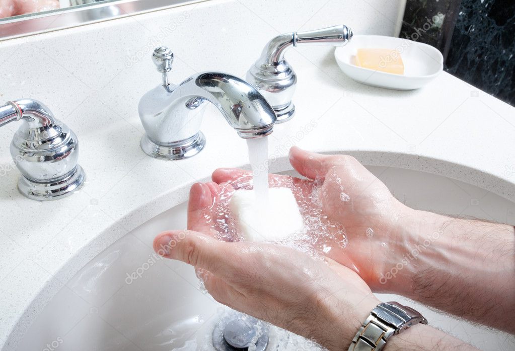 Washing hands with soap in washroom sink