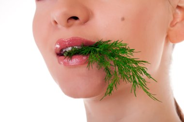 Young female model holding a batch of fresh green dill in her teeth clipart