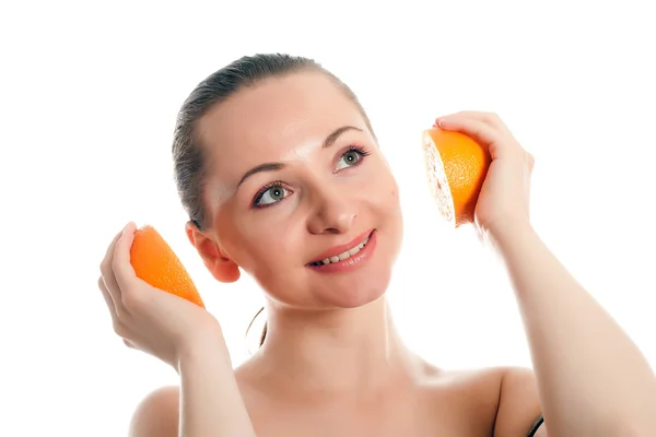 Mulher segurando metades de laranjas como fones de ouvido — Fotografia de Stock