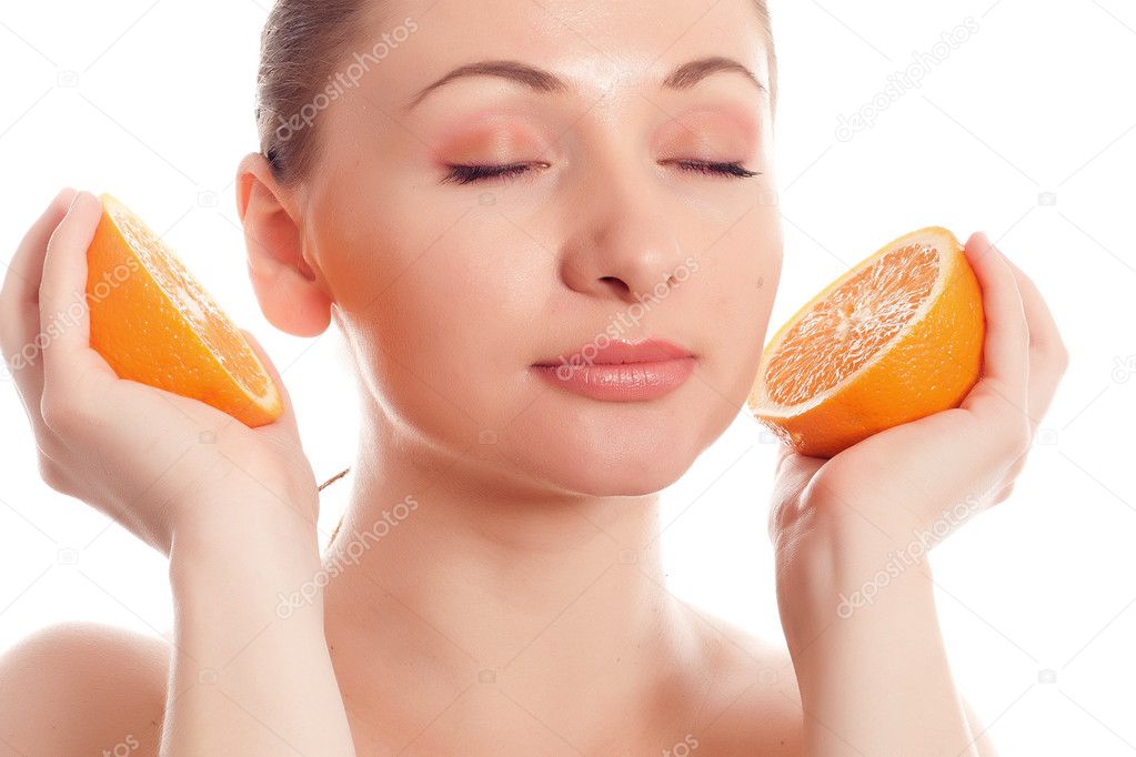 Woman holding halves of oranges as headphones