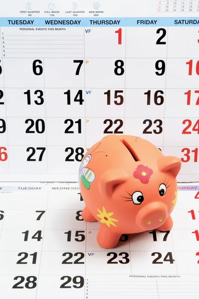 Sparschwein auf Kalenderblättern — Stockfoto
