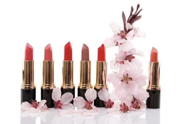 Diferentes lápiz labial rojo y flor de cereza, concepto de belleza —  Fotos de Stock