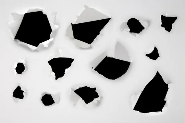 Fechar-se de uns buracos escuros no jogo de papel branco — Fotografia de Stock