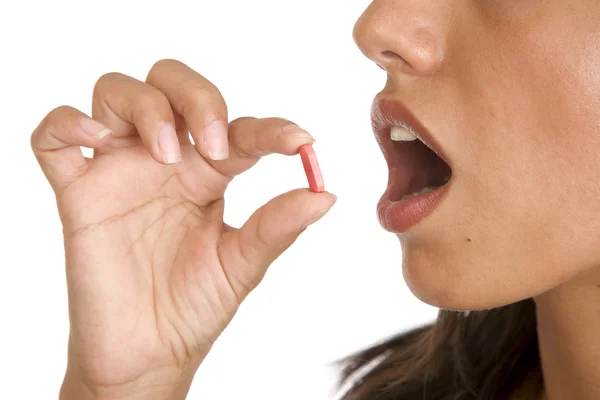 Jovens mulheres pops um comprimido em sua boca — Fotografia de Stock