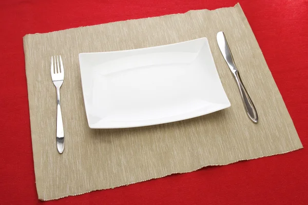 लाल टेबल पर सफेद प्लेट फोर्क और चाकू — स्टॉक फ़ोटो, इमेज