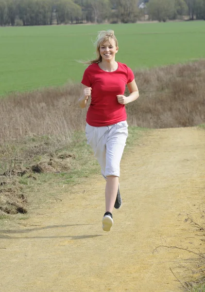 Frau joggt auf Feldweg — Stockfoto