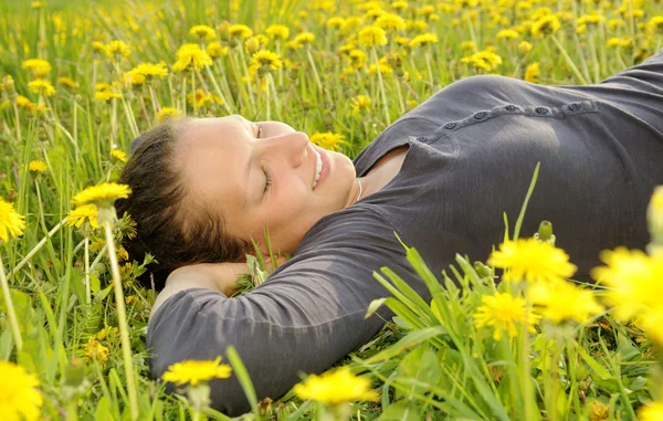 Frau liegt auf einer Blumenwiese — Stockfoto