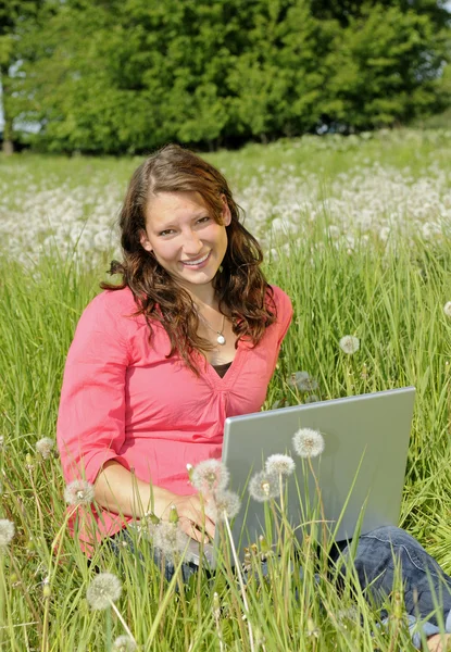 在一片草地上的笔记本电脑的女人 — 图库照片