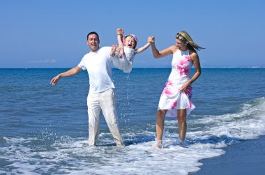 Young family playing with daughter on beach in Spain clipart