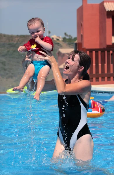 年轻的女人和女儿在泳池玩 — 图库照片