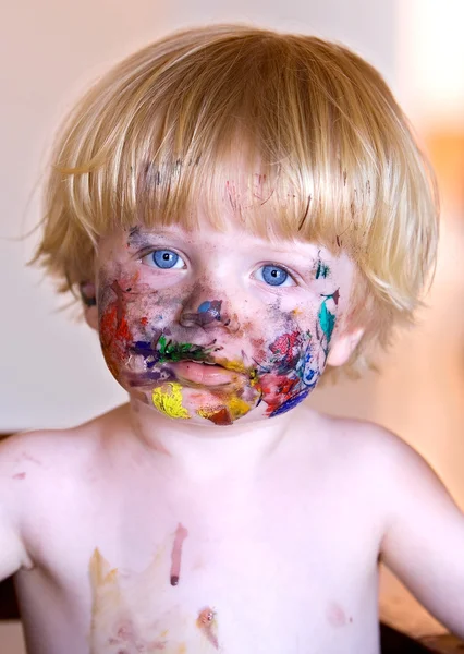 Young boy with face covered in colourful paint — Stock Photo, Image
