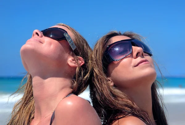 Dos mujeres jóvenes atractivas tomando el sol en una playa de arena —  Fotos de Stock