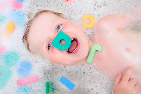 Молодий хлопчик грає у бульбашковій ванні з пінистими літерами — стокове фото