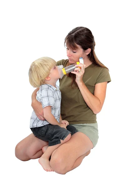 그녀의 아들에 게 호흡기 약을 주는 젊은 어머니 스톡 사진