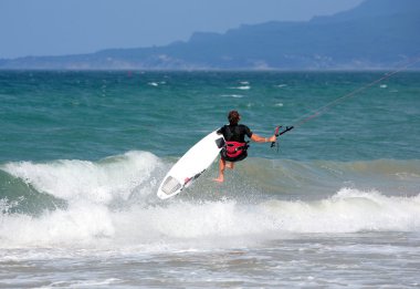 Young male kitesurfer jumping on the sea clipart