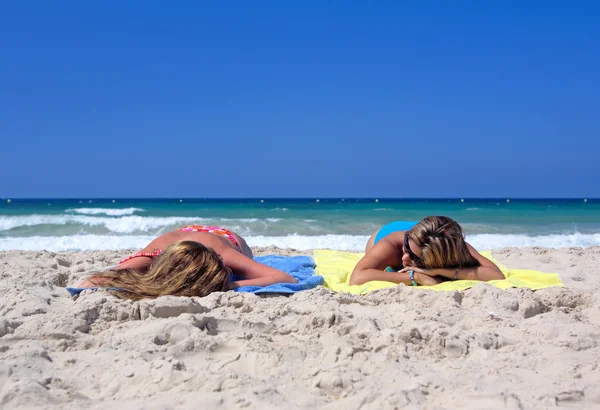 Dos chicas jóvenes sexy que yacen en una playa soleada de vacaciones o holi —  Fotos de Stock