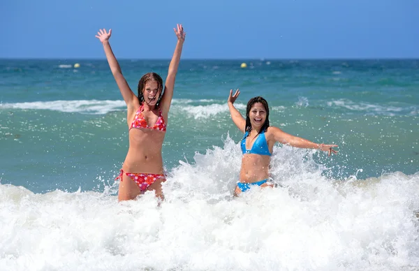 Two attractive young girl friends playing in the sea on vacation — Stock Photo, Image