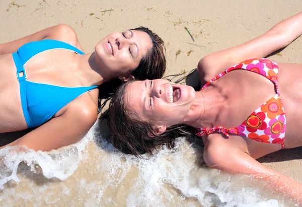 Duas jovens mulheres atraentes salpicadas por onda fria na praia — Fotografia de Stock