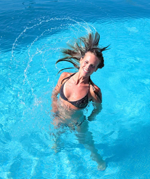 Atraente jovem bronzeada jogando o cabelo de volta na piscina — Fotografia de Stock