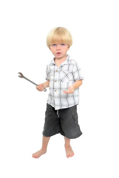 Изолированный снимок мальчика, играющего с большим гаечным ключом — стоковое фото