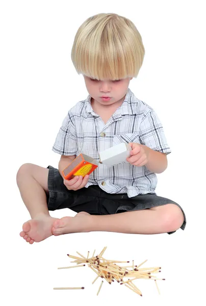 Young boy playing with matches on a white background — Stock Photo, Image