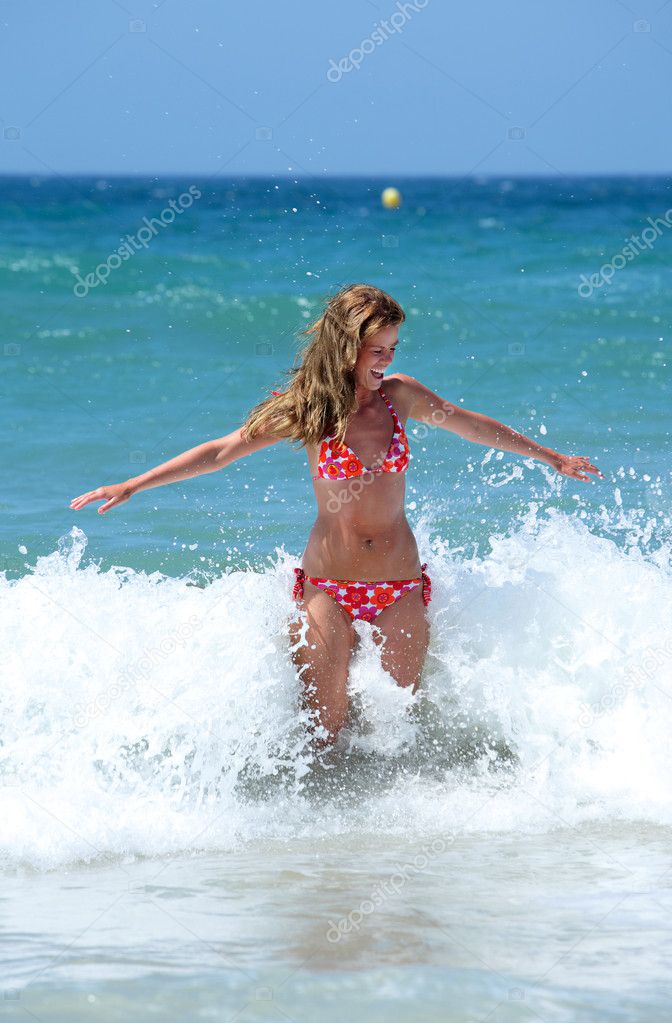 Sexy fit young woman being splashed by a wave