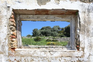 Spanish countryside seen through hole in wall of ruins clipart