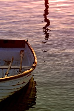 Old Rowing Boat with Oars on Sea During Sunset clipart