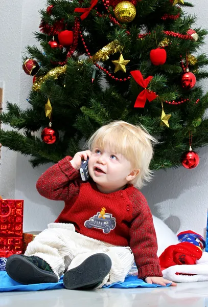 Young boy or toddler talking on mobile phone under a christmas t — Stock Photo, Image