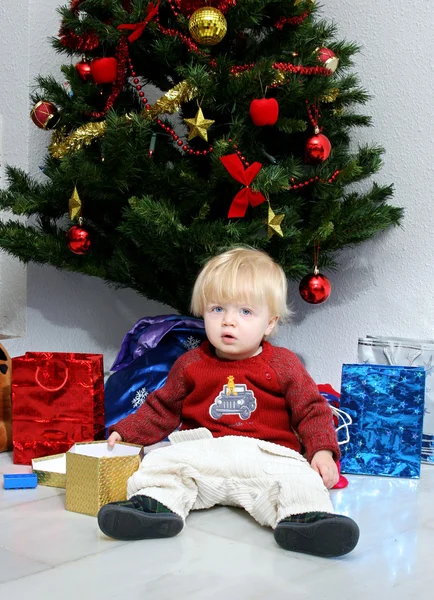 Young boy or toddler sitting under a christmas tree — Stock Photo, Image
