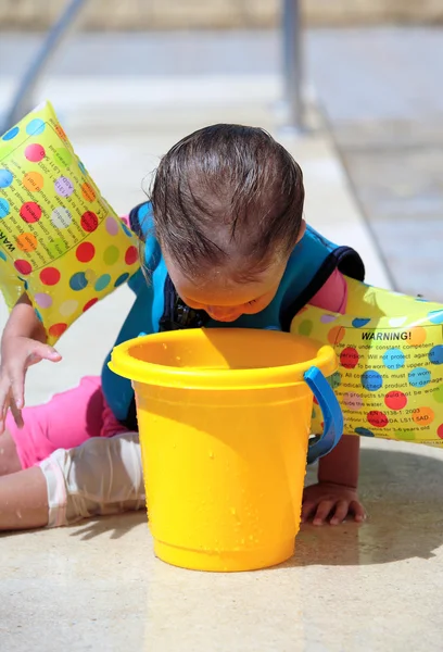 Girl toddler sitting next to swimming pool — Stock Photo, Image