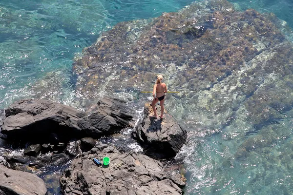 Veduta aerea di giovane donna che pesca su rocce con rete — Foto Stock