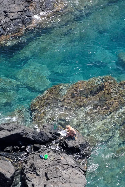 Vue aérienne de la jeune femme pêchant sur des rochers avec filet — Photo
