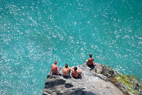 Quatre jeunes garçons assis rochers regardant le jour passer — Photo