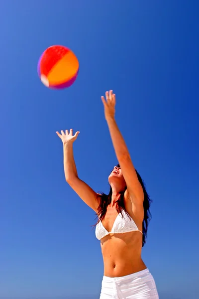 Menina captura bola de praia na praia ensolarada na Espanha com céu azul — Fotografia de Stock