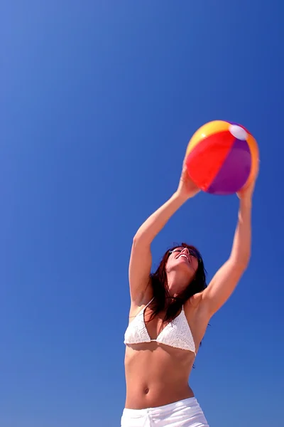 Woman catching beach ball with blue sky behind — Stock Photo, Image