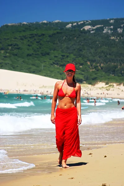 Muchacha joven atractiva en sarong rojo, bikini y gorra de béisbol wal — Foto de Stock