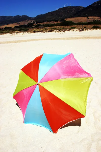 Πολύχρωμο γύρο ομπρέλα στη λευκή αμμουδιά με γαλάζιο ηλιόλουστο ουρανό — Φωτογραφία Αρχείου