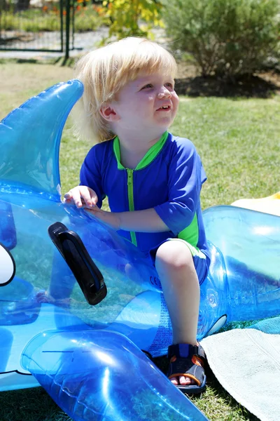 Young boy or child sitting on inflatable dolphin by swimming poo — Stock Photo, Image