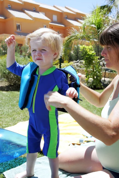 Νεαρή μητέρα που προετοιμάζει το παιδί για μάθημα κολύμβησης — Φωτογραφία Αρχείου