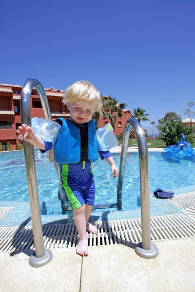 Мальчик вылезает из бассейна на каникулах — стоковое фото