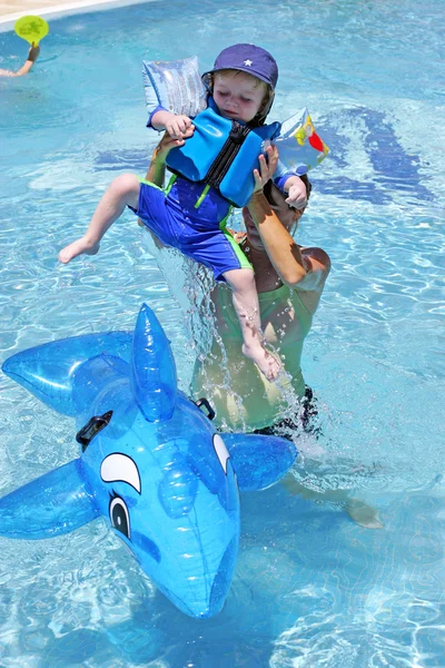 Young boy in buoyancy suit being taught to swim by his pregnant — Stock Photo, Image
