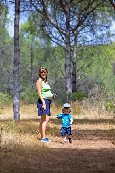 Jonge moeder en zoon wandelen door bos — Stockfoto