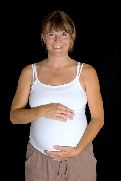 Mujer embarazada sosteniendo el estómago y sonriendo — Foto de Stock